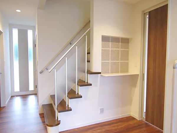 玄関を開けると空間の広がりを考えて設計された階段が配置されています。正面の飾り棚もポイントです。