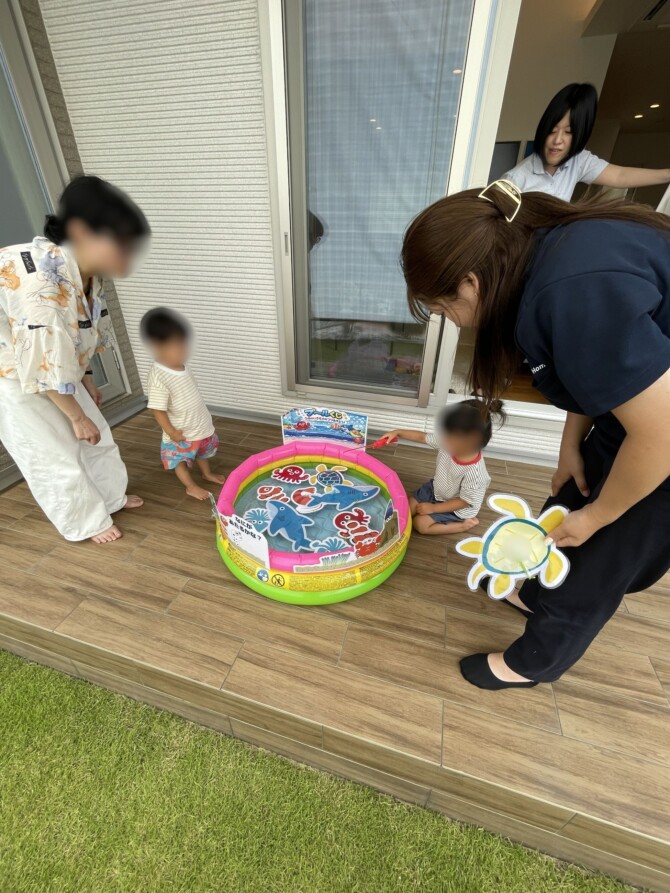 タイルデッキに置いたプールで釣り遊びをしている家族