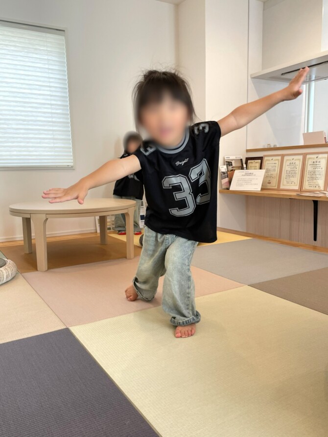 畳コーナーで飛行機のポーズをとっている男の子