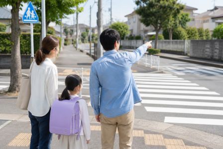 横断歩道や歩道を確認しながら通学路を見学している家族