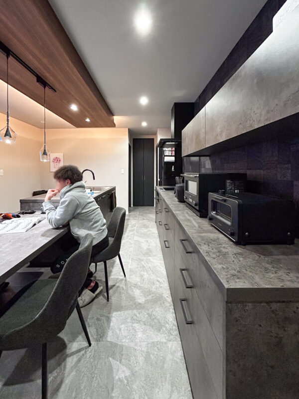 キッチンのタイル床とグラフテクトのダイニングテーブルとカップボード