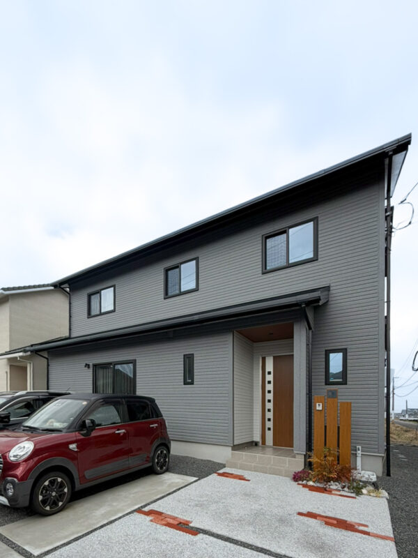 木目の機能門柱に、コンクリート洗い出し仕上げにレンガをあしらったアプローチ