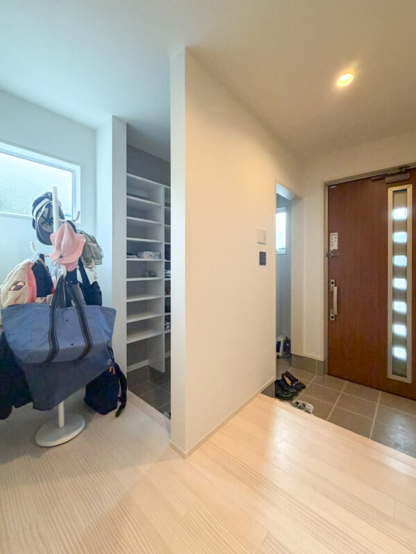 アイボリーカラーの無垢床に石目調でライトグレーカラーのクロスをあわせたホール