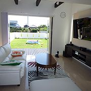 ハワイをイメージした家具がコーディネートされており、フルオープンサッシを採用。室内側とウッドデッキの段差をなくし、外と中との一体感を高めた開放的なリビングです。