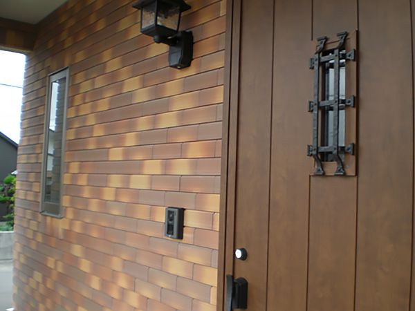 茶系の重厚感ある外壁に合わせて採用した木調の玄関ドアは、家全体の雰囲気によく馴染みます。