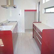 赤いキッチンの横には階段下を利用したパントリーがあるので収納もたくさん可能です。赤いロールルスクリーンもいい感じです。