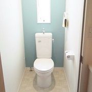 1階トイレはタンクレス風のトイレを採用しました。トイレ、手洗器、手摺は白で統一していますが、一部のクロスの色を変更しています。敢えて濃いグレーを設ける事で白い手洗器とお客様がご自分で購入されたﾍﾟｰﾊﾟｰﾎﾙﾀﾞｰとﾀｵﾙﾘﾝｸﾞが映えるようになってます。2階トイレは明るいブルーを採用しました。これもまたトイレの白さとマッチして、清潔感がありながらもちょっとした遊びを含んだ空間に仕上がりました。
