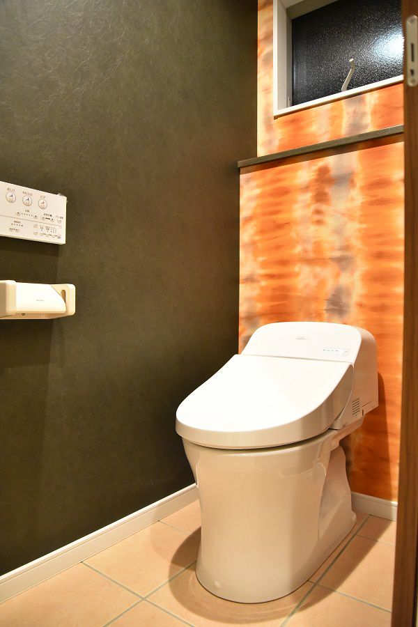 一階のトイレは、床はタイルで仕上げ、壁にはインパクトのある壁紙を張り上げました。