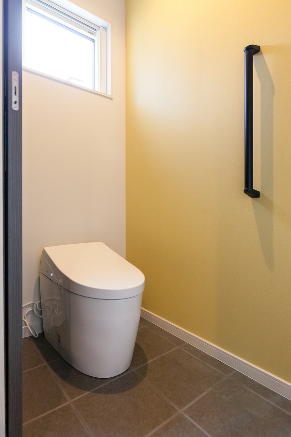 トイレの床はタイル仕様でお掃除のしやすさがポイント。アクセントウォールは黄色系で明るく温かみのある印象