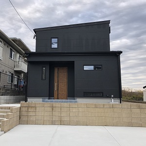 外壁のデザインはアークディンプル（コンクリート打ちっぱなし風）にし、塗装は黒で仕上げました。屋根や窓周りも黒でそろえ、統一感があってモダンなかっこいい外観です。
