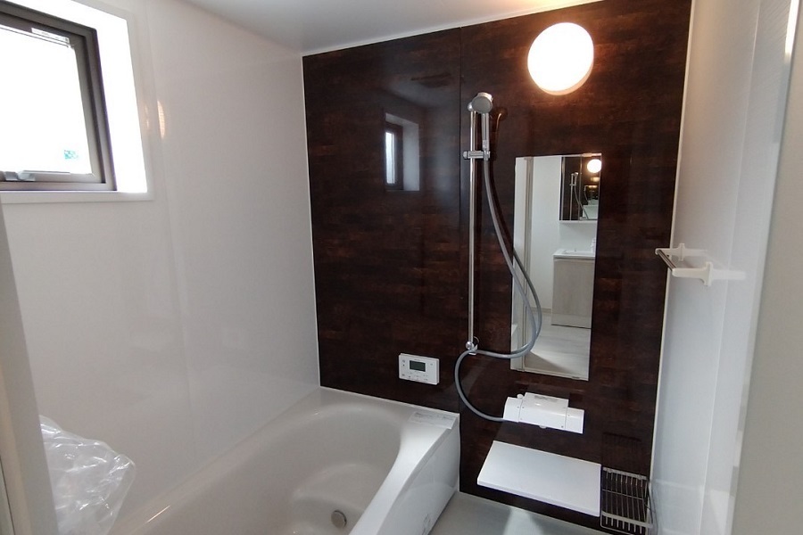 濃いブラウンの木目調のアクセントパネルが印象的な浴室です。